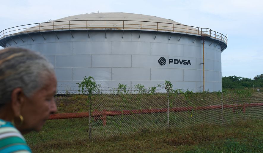 A woman walks near of a oil storage tank of Venezuela's state-run oil company, PDVSA in Cabimas, Venezuela, Tuesday, Sep. 1, 2026. (AP Photo/Ariana Cubillos)