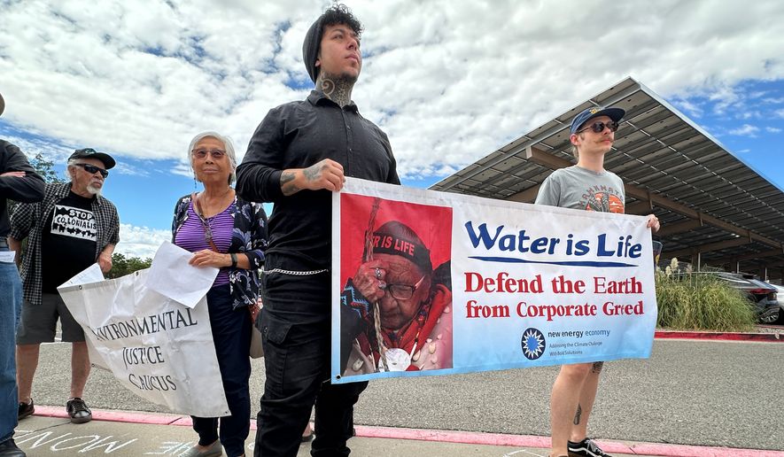 Protesters hold signs in opposition of the Project Jupiter data center during a demonstration outside a state office in Santa Fe, N.M., Friday, Aug. 21, 2026. (AP Photo/Susan Montoya Bryan)