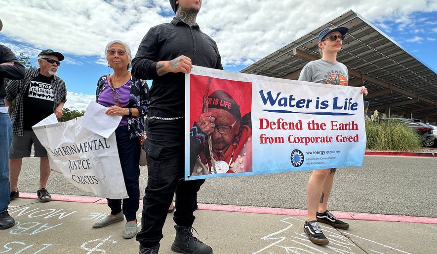 Protesters hold signs in opposition of the Project Jupiter data center during a demonstration outside a state office in Santa Fe, N.M., Friday, Aug. 21, 2026. (AP Photo/Susan Montoya Bryan)