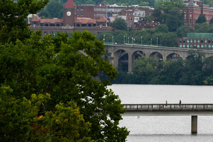 People cross a pedestrian bridge from Roosevelt Island Park, Sunday, Aug. 30, 2026, in Washington. (AP Photo/Julia Demaree Nikhinson)