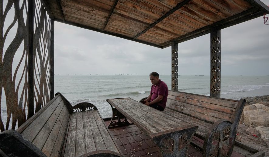 A man rests at a waterfront shelter as commercial vessels lie anchored in the Strait of Hormuz off Bandar Abbas, Iran, Friday, Sept. 4, 2026. (AP Photo/Vahid Salemi)