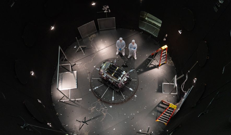 FILE - This photo provided by NASA shows Kieran Wilson, LINK's principal investigator, and Hunter Robertson, a space systems engineer, both at Katalyst Space, standing next to their spacecraft inside the SES (Space Environment Simulator) at NASA's Goddard Space Flight Center in Greenbelt, Md., April 17, 2026, ahead of thermal vacuum testing. (Sophia Roberts/NASA via AP, File)