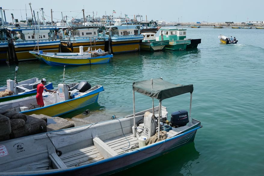 A man works aboard a boat as a motorboat leaves a harbor in Bandar Abbas, Iran, Sunday, Sept. 6, 2026. (AP Photo/Vahid Salemi)