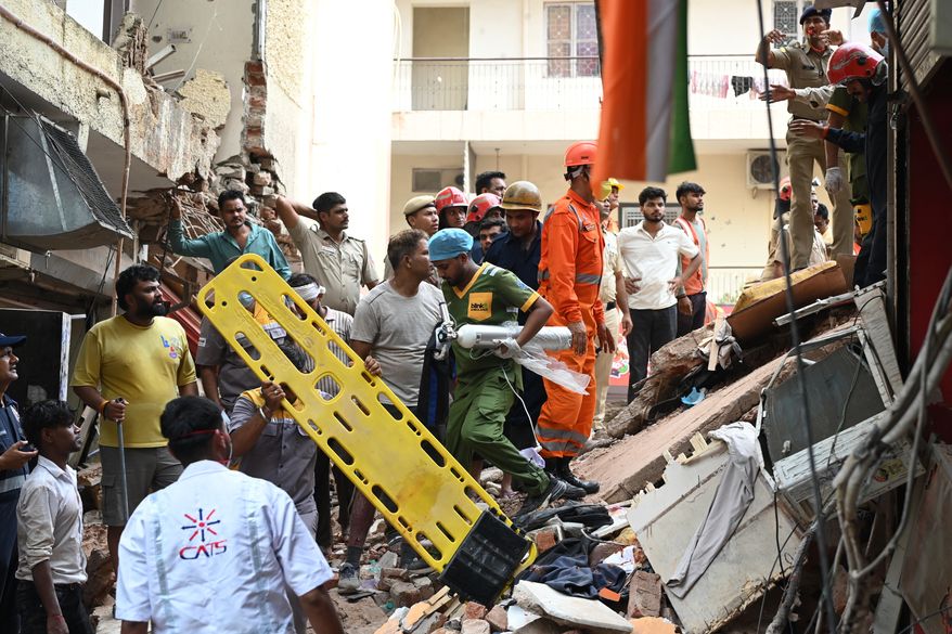 Rescue workers look for the trapped survivors under the debris of a building that collapsed in New Delhi, India, Sunday, Sept. 6, 2026. (AP Photo/ Vipin)