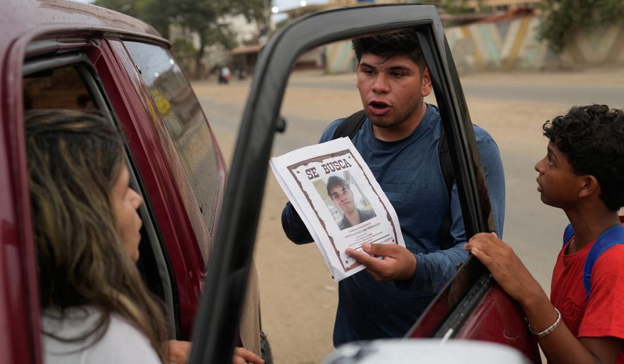 Pedro Gomez asks people about his cousin, Andres Molina, who has been missing since the earthquakes, in La Guaira, Venezuela, Saturday, Aug. 22, 2026. (AP Photo/Ariana Cubillos)