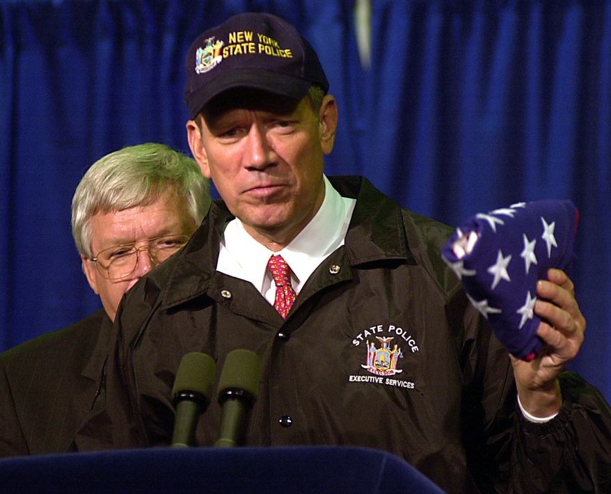 New York Gov. George Pataki holds an American flag, which earlier flew over the capital, that was given to him by House Speaker Dennis Hastert, back left, Monday, Oct. 1, 2001, in New York. More than 100 congressional members toured the site of the World Trade Center. (AP Photo/Tony Gutierrez)