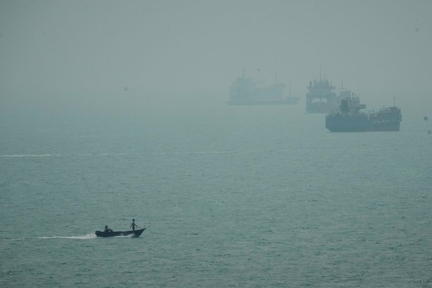 A motorboat travels past commercial vessels anchored amid haze in the Strait of Hormuz off Bandar Abbas, Iran, Monday, Sept. 7, 2026. (AP Photo/Vahid Salemi)