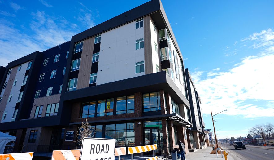 FILE - A person sweeps outside during the grand opening of the Rose on Colfax, a new affordable housing community with a co-located childcare center in the East Colfax neighborhood, Jan. 24, 2024, in Denver. (AP Photo/David Zalubowski, File)