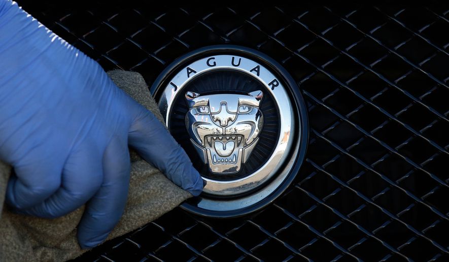 FILE - A worker polishes a Jaguar logo on a car at a Jaguar dealer in London, Wednesday Sept. 28, 2016. (AP Photo/Frank Austin, File)