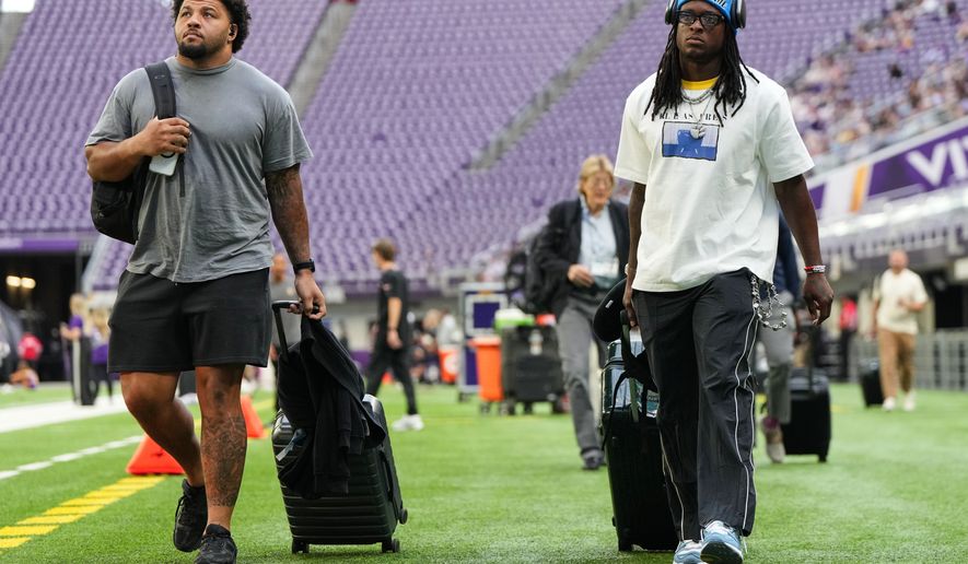 From left, Baltimore Ravens guard Jovaughn Gwyn and safety K'von Wallace arrive before a preseason NFL football game against the Minnesota Vikings, Saturday, Aug. 22, 2026, in Minneapolis. (AP Photo/Abbie Parr)