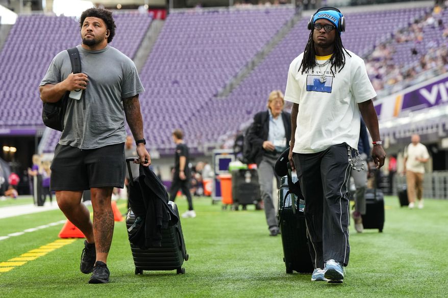 From left, Baltimore Ravens guard Jovaughn Gwyn and safety K'von Wallace arrive before a preseason NFL football game against the Minnesota Vikings, Saturday, Aug. 22, 2026, in Minneapolis. (AP Photo/Abbie Parr)