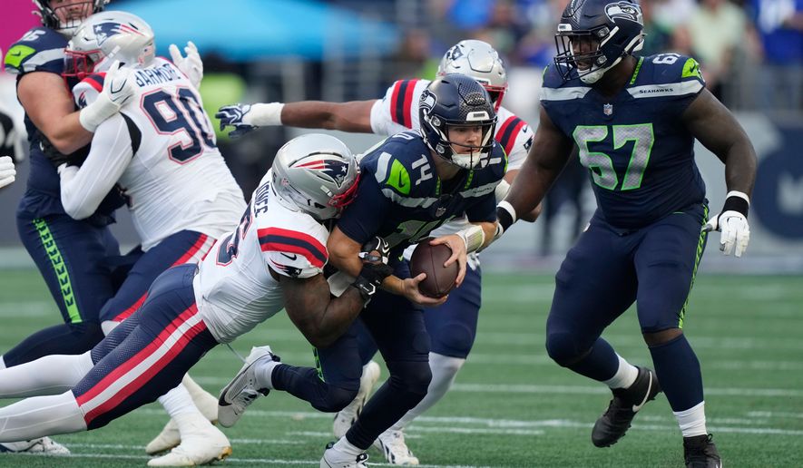 Seattle Seahawks quarterback Sam Darnold, center, is sacked by New England Patriots linebacker Dre'mont Jones, left, as Seattle Seahawks linebacker Connor O'Toole is at right, during the first half of an NFL football game, Wednesday, Sept. 9, 2026, in Seattle. (AP Photo/Stephen Brashear)