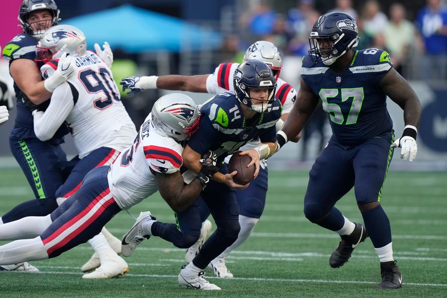 Seattle Seahawks quarterback Sam Darnold, center, is sacked by New England Patriots linebacker Dre'mont Jones, left, as Seattle Seahawks linebacker Connor O'Toole is at right, during the first half of an NFL football game, Wednesday, Sept. 9, 2026, in Seattle. (AP Photo/Stephen Brashear)