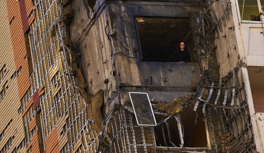 A woman peers from a window of a partially damaged residential building following a Russian drone attack in Kyiv, Ukraine, Wednesday, Sept. 9, 2026. (AP Photo/Francisco Seco)