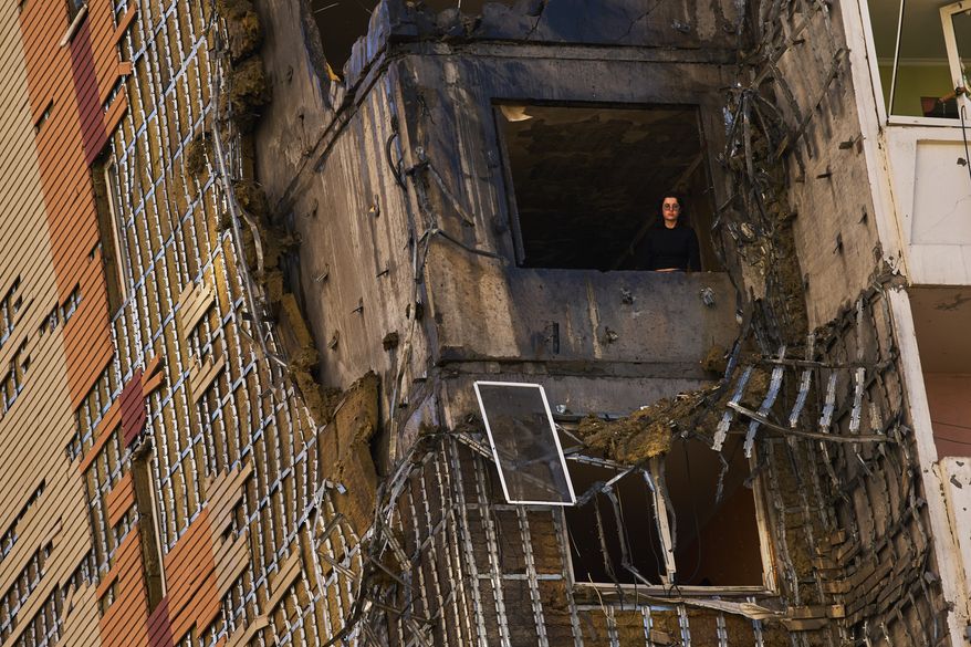 A woman peers from a window of a partially damaged residential building following a Russian drone attack in Kyiv, Ukraine, Wednesday, Sept. 9, 2026. (AP Photo/Francisco Seco)
