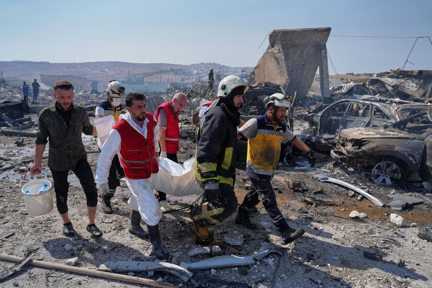 Civil defense workers and a firefighter remove a body from the site of an explosion at what Syria's Defense Ministry said was a warehouse used for the temporary storage of weapons near Sarmada, in Idlib province, Syria, Wednesday, Sept. 9, 2026. (AP Photo/Omar Albam)