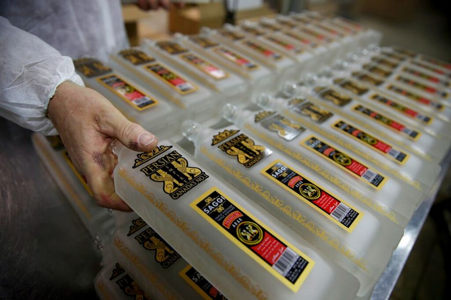 In this April 12, 2019, file photo, an employee prepares to fill bottles of "Arak Saggi" at the Persian Empire Distillery in Peterborough, Canada, about 70 miles northeast of Toronto. Arak Saggi is a liquor made of raisin paste imported from California that has a taste similar to grappa, the Italian grape-based brandy. (AP Photo/Kamran Jebreili) ** FILE **