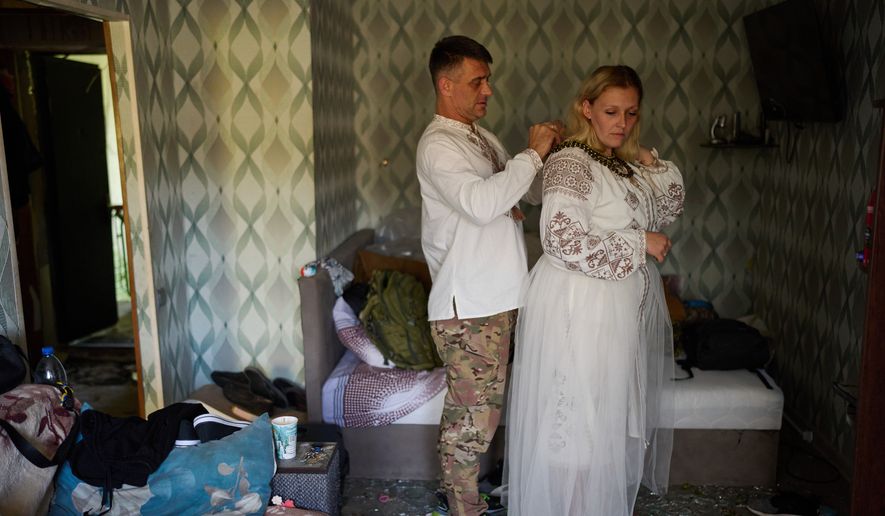 Liudmyla Ryzhak, right, and her fiancee Leonid Ryzhak get ready for their wedding ceremony in their damaged apartment, following a Russian missile and drone attack in Kyiv, Ukraine, Tuesday, Sept. 8, 2026. (AP Photo/Francisco Seco)