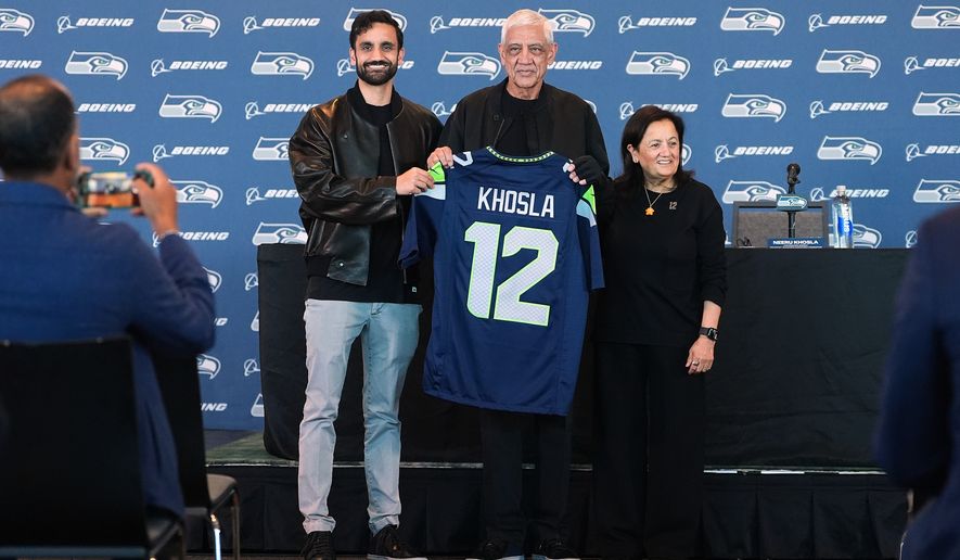Seattle Seahawks owners, from left, Vice Chair Neal Khosla, Chair Vinod Khosla and Controlling Owner & President of the Seahawks Charitable Foundation Neeru Khosla pose with a Seahawks jersey before a news conference before an NFL football game between the Seahawks and the New England Patriots, Wednesday, Sept. 9, 2026, in Seattle. (AP Photo/Lindsey Wasson)