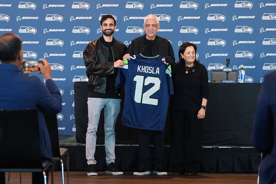 Seattle Seahawks owners, from left, Vice Chair Neal Khosla, Chair Vinod Khosla and Controlling Owner & President of the Seahawks Charitable Foundation Neeru Khosla pose with a Seahawks jersey before a news conference before an NFL football game between the Seahawks and the New England Patriots, Wednesday, Sept. 9, 2026, in Seattle. (AP Photo/Lindsey Wasson)