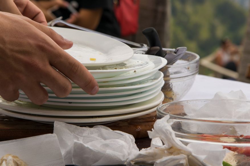 Stacking dirty plates at a restaurant after you finish a meal might reveal more about your childhood than you realize. (Photo by 682A IA on Shutterstock)
