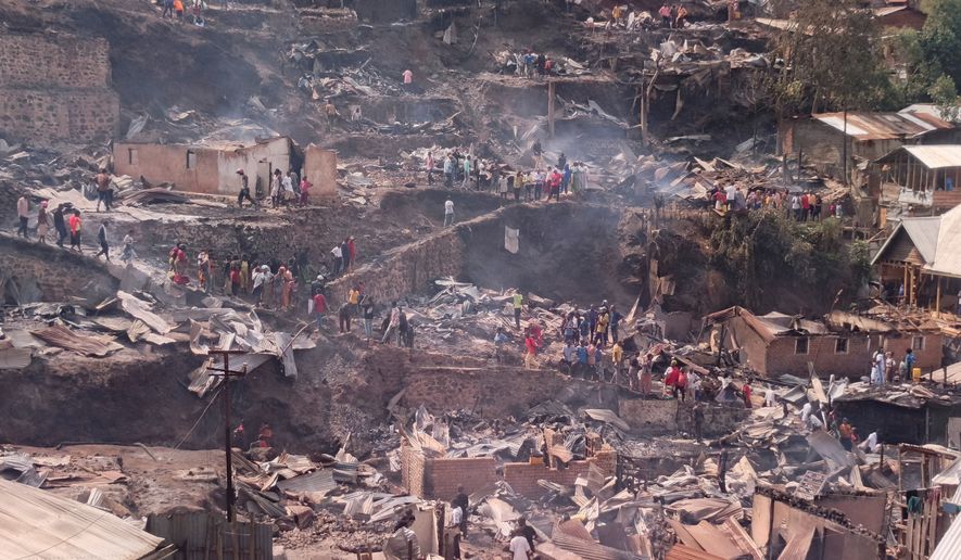 People walk amid the charred remains of homes near a primary school and a secondary school where a fire broke out, killing several students, in Bukavu, Congo, Thursday, Sept. 10, 2026. (AP Photo/Janvier Barhahiga)