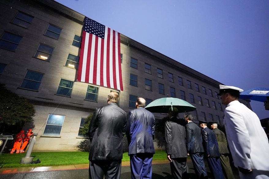 Secretary of Defense Pete Hegseth, Chairman of the Joint Chiefs, Air Force Gen. Dan Caine, and other officials, watch as the flag is unfurled at the Pentagon, Friday, Sept. 11, 2026, in Arlington, Va. (AP Photo/Manuel Balce Ceneta)