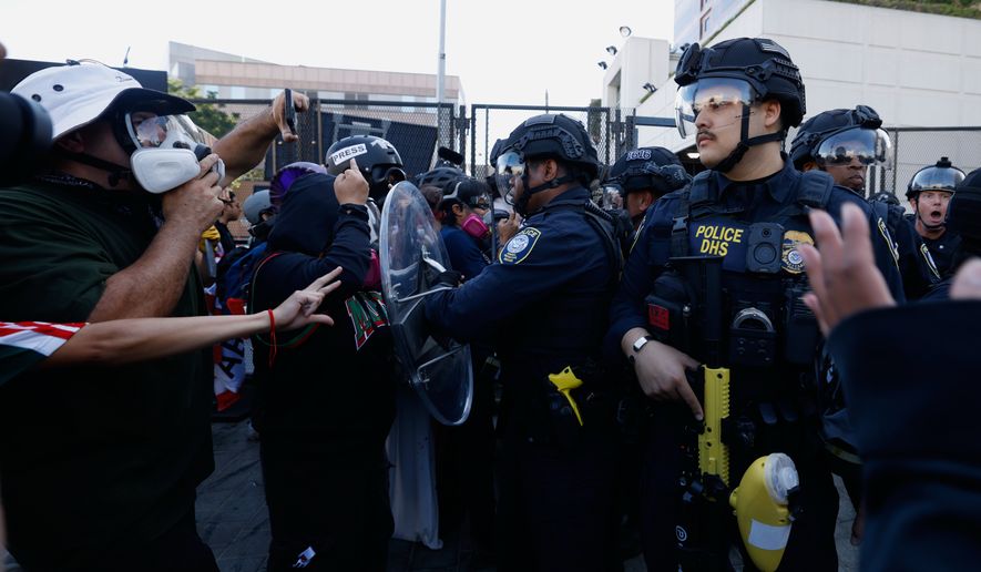 Protesters confront federal law enforcement agents outside the Metropolitan Detention Center on June 6, 2026, commemorating federal immigration raids and community protests one year ago in Los Angeles. (AP Photo/Jill Connelly, File)