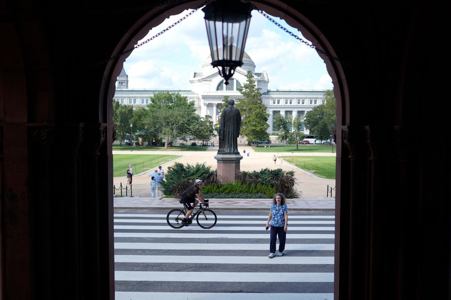 FILE - People are seen near the main entrance to the Smithsonian Institution Building, more commonly known as the Smithsonian Castle, which is closed for renovations, in Washington, Tuesday, Sept. 8, 2026. (AP Photo/Pablo Martinez Monsivais,FIle)