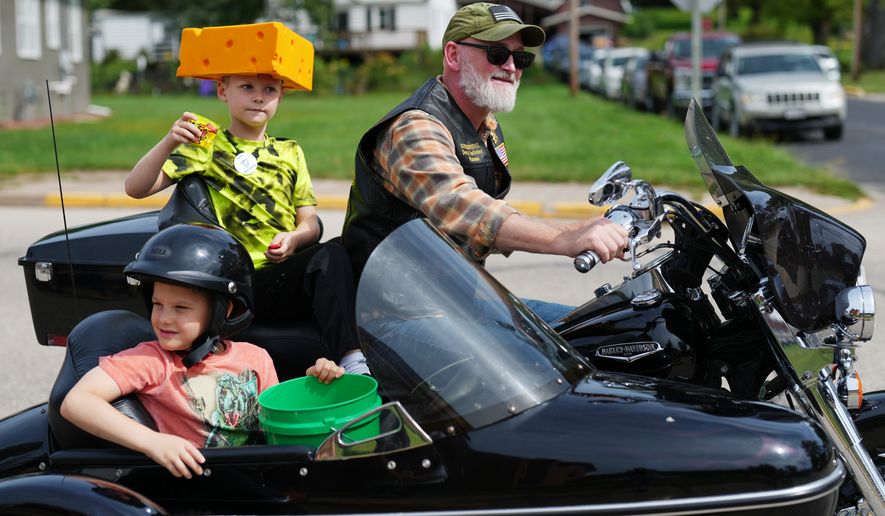 U.S. Rep. Derrick Van Orden rides his motorcycle in a Labor Day parade with his grandsons, Teddy and Henry, Monday, Sept. 7, 2026, in Readstown, Wis. (AP Photo/Ellen Schmidt)