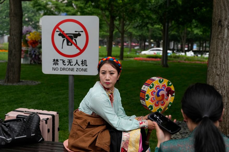 A performer rests near a "No Drone Zone" sign in Beijing, on May 31, 2023. (AP Photo/Ng Han Guan)
