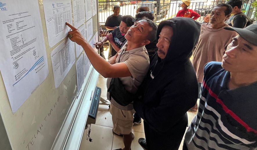 People check the passenger manifest of Virgo Transport 8 passenger ferry which overturned in bad weather in the Java Sea, at the rescuers' command center in Banjarmasin, South Kalimantan, Indonesia, Monday, Sept. 14, 2026. (AP Photo/Iman Satria)
