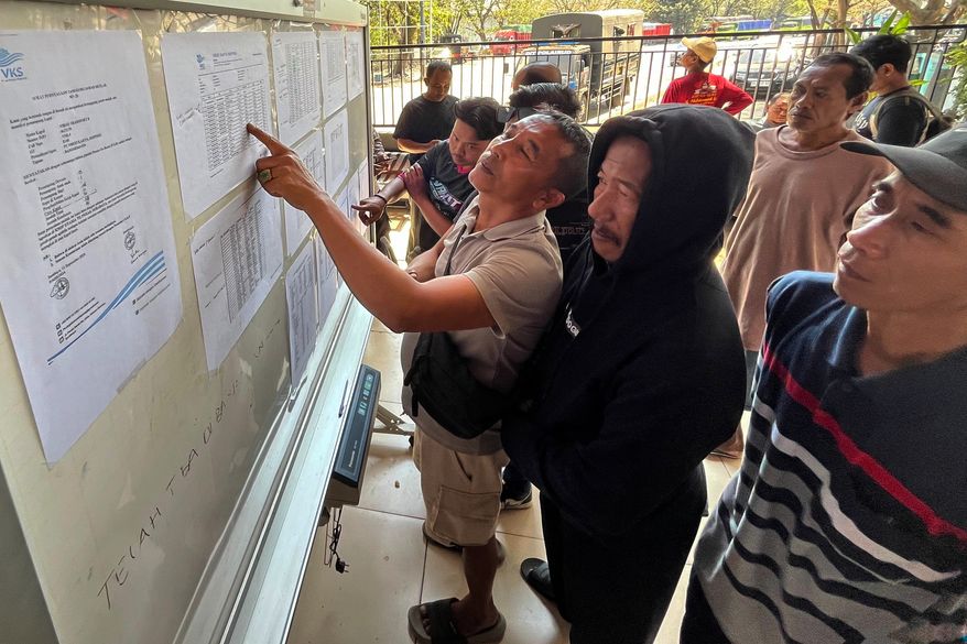 People check the passenger manifest of Virgo Transport 8 passenger ferry which overturned in bad weather in the Java Sea, at the rescuers' command center in Banjarmasin, South Kalimantan, Indonesia, Monday, Sept. 14, 2026. (AP Photo/Iman Satria)