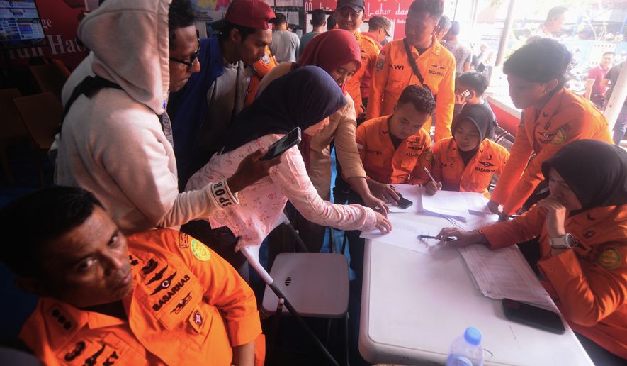 People look for the names of their family members on a passenger list after a ferry overturned in bad weather in the Java Sea, at the rescuers command center in Banjarmasin, South Kalimantan, Indonesia, Sunday, Sept. 13, 2026. (AP Photo/Iman Satria)