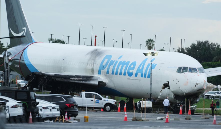 Workers inspect an Amazon cargo plane that overshot a runway four days ago at Miami International Airport, Thursday, Sept. 10, 2026, in Miami. (AP Photo/Marta Lavandier)