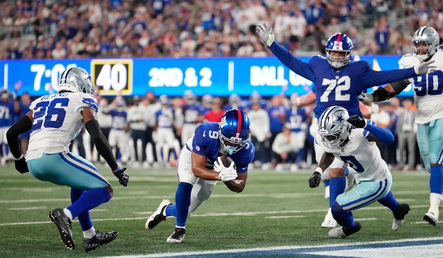 New York Giants tight end Isaiah Likely (9), with teammate guard Jermaine Eluemunor (72) reacting, scores a touchdown run between Dallas Cowboys cornerback Daron Bland (26) and linebacker DeMarvion Overshown (0 ) during the second half of an NFL football game Sunday, Sept. 13, 2026, in East Rutherford, N.J. (AP Photo/Yuki Iwamura)