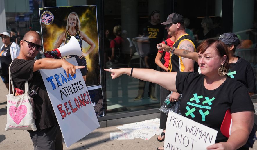 People hold signs and point after comments on transgender athletes made by Indiana Fever guard Sophie Cunningham, before a WNBA basketball game between the Minnesota Lynx and Indiana Fever, Aug. 2, 2026, in Minneapolis. (AP Photo/Abbie Parr, File)