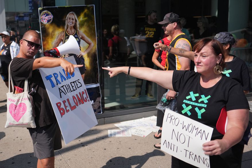People hold signs and point after comments on transgender athletes made by Indiana Fever guard Sophie Cunningham, before a WNBA basketball game between the Minnesota Lynx and Indiana Fever, Aug. 2, 2026, in Minneapolis. (AP Photo/Abbie Parr, File)