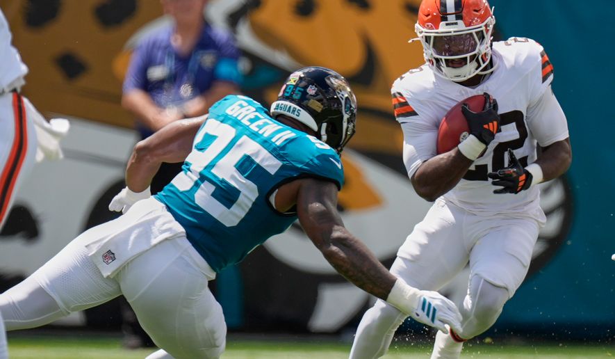 Cleveland Browns running back Dylan Sampson (22) carries against Jacksonville Jaguars defensive end B.J. Green II (95) in the first half of an NFL football game, Sunday, Sept. 13, 2026, in Jacksonville. (AP Photo/Mike Stewart)