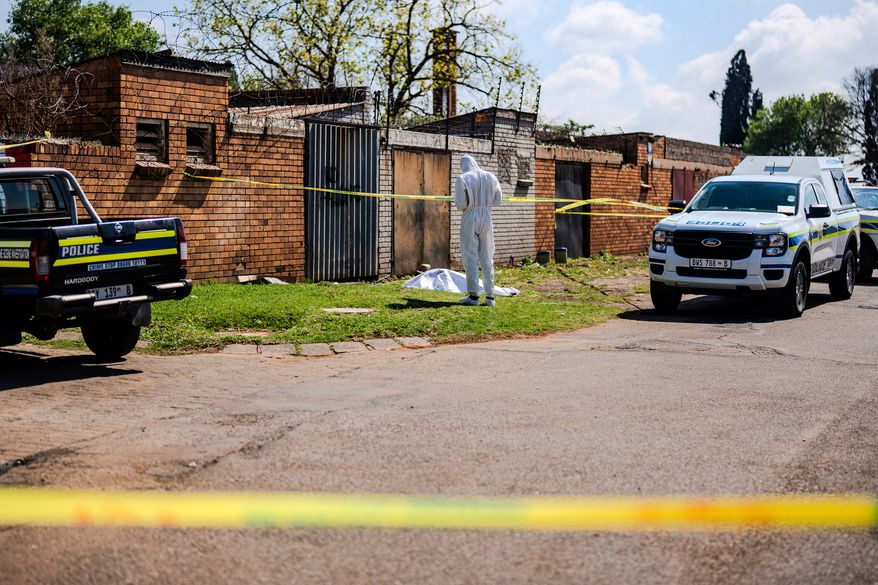 A forensic officer works at the scene where a sixth body, believed to be that of a woman, was found along a road in KwaThema, Springs, South Africa, Tuesday, Sept. 15, 2026. (AP Photo)