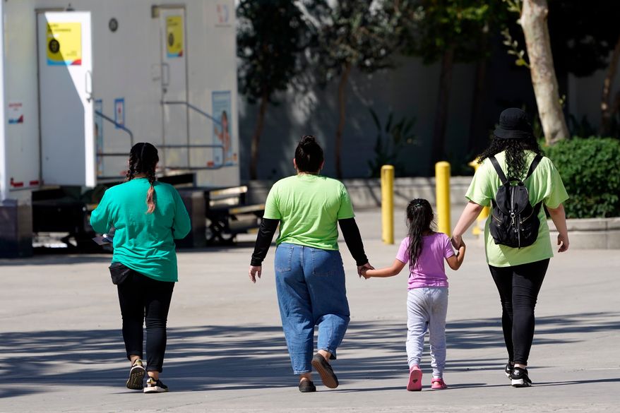FILE - A child holds hands with workers at an emergency shelter for migrant children, July 2, 2021, in Pomona, Calif. (AP Photo/Marcio Jose Sanchez, Pool, File)