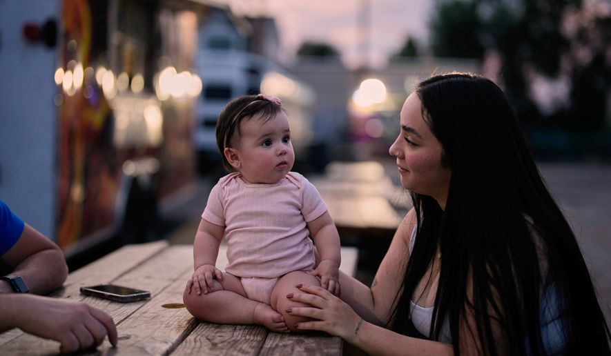 A Venezuelan mother sits with her daughter among food trucks Tuesday, July 14, 2026, in Midvale, Utah. (AP Photo/Gregory Bull)