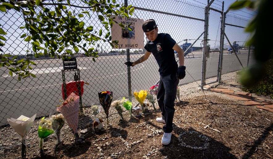 A person adjusts flowers at a memorial for Eliana Moreno and George Marciniw who died in a helicopter crash at the site where their helicopter used to park at Whiteman Airport in Los Angeles, Wednesday, Sept. 16, 2026. (AP Photo/Ethan Swope)