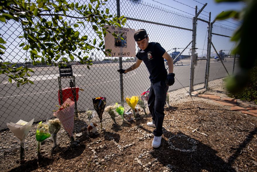 A person adjusts flowers at a memorial for Eliana Moreno and George Marciniw who died in a helicopter crash at the site where their helicopter used to park at Whiteman Airport in Los Angeles, Wednesday, Sept. 16, 2026. (AP Photo/Ethan Swope)