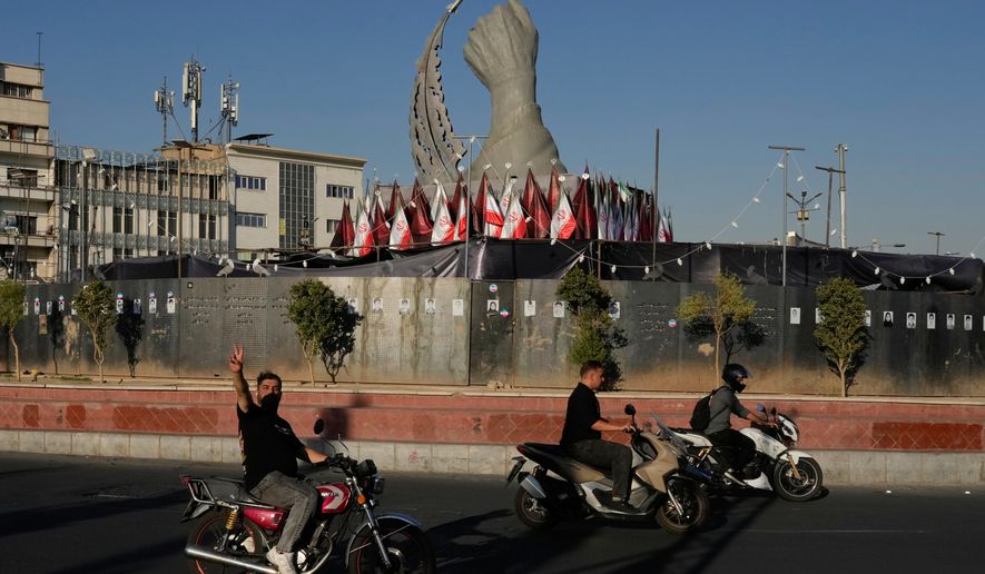 A man reacts to the camera while driving past a monument depicting the clenched fist of the late Iranian Supreme Leader Ayatollah Ali Khamenei, who was killed in the U.S. and Israel strike on Feb. 28, and a missile at the Islamic Revolution square in downtown Tehran, Iran, Tuesday, Sept. 15, 2026. (AP Photo/Vahid Salemi)