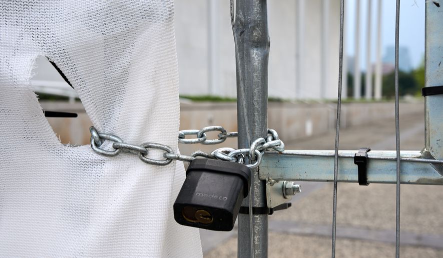 The Kennedy Center, which has been fenced off and closed to the public, is seen through a hole in a covered fence, Thursday, Sept. 17, 2026, in Washington. (AP Photo/Jacquelyn Martin)