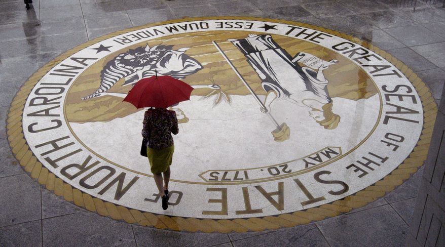 A woman carrying an umbrella leaves the N.C. Legislative Building in Raleigh, N.C., on Thursday, June 2, 2005. (AP Photo/Karen Tam)