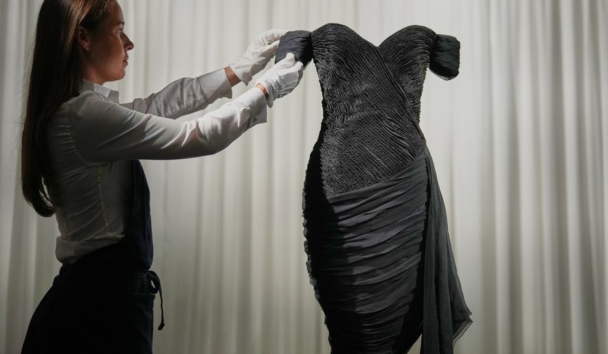 A dress worn by the late Princess Diana and known as the ''Revenge Dress'', designed by Christina Stambolian, is unveiled by staff at Sotheby’s auction house in London, Friday, Sept. 18, 2026, ahead of its Dec. 9 auction in New York, where it is estimated to sell for US$150,000-300,000. (AP Photo/Alastair Grant)