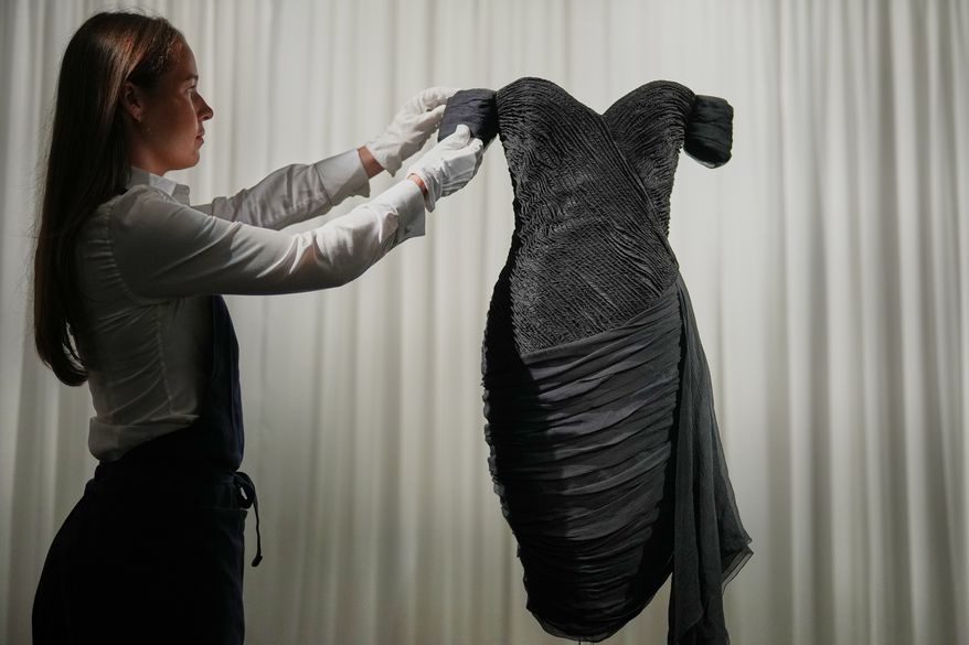 A dress worn by the late Princess Diana and known as the ''Revenge Dress'', designed by Christina Stambolian, is unveiled by staff at Sotheby’s auction house in London, Friday, Sept. 18, 2026, ahead of its Dec. 9 auction in New York, where it is estimated to sell for US$150,000-300,000. (AP Photo/Alastair Grant)