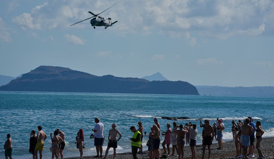 Tourists from nearby hotels watch a military helicopter fly overhead during Medusa 15, a multinational military exercise led by Greece and Egypt, at Maleme on the Greek island of Crete, Friday, Sept. 18, 2026. (AP Photo/Thanassis Stavrakis)